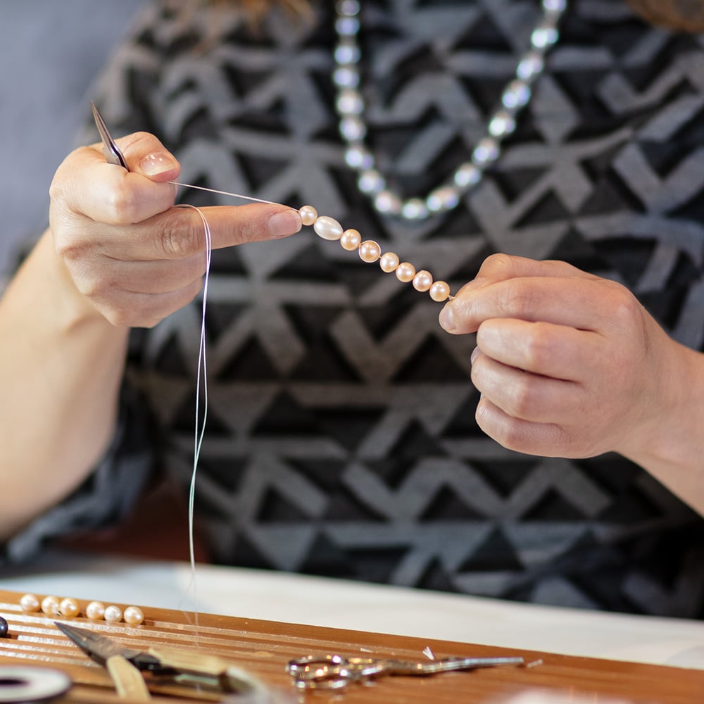 someone restringing pearls in the design studio at isle of wight pearl
