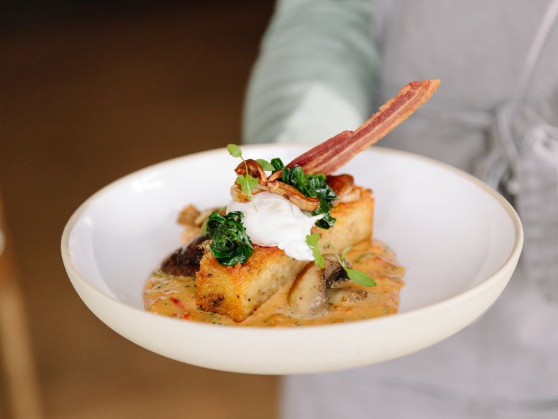 waiter holding plate of gourmet hash browns from isle of wight cafe menu