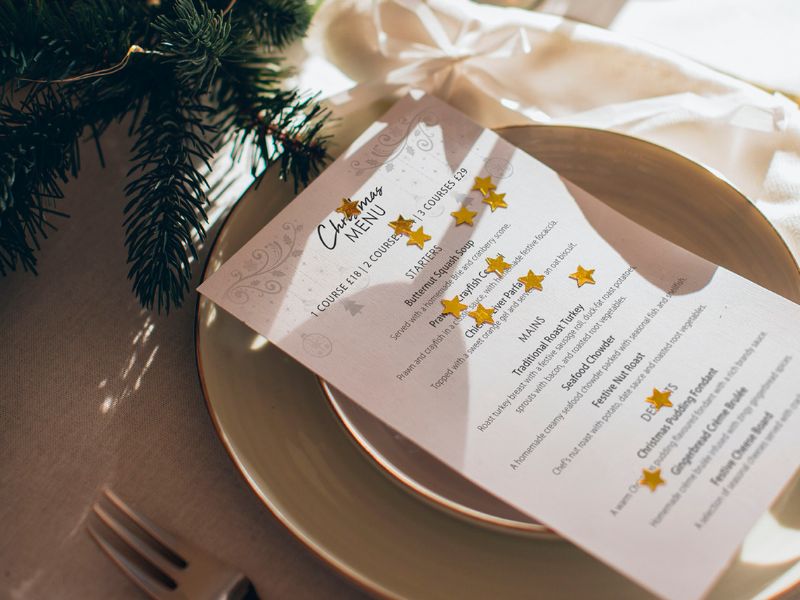 Christmas menu resting on a plate with gold stars on top